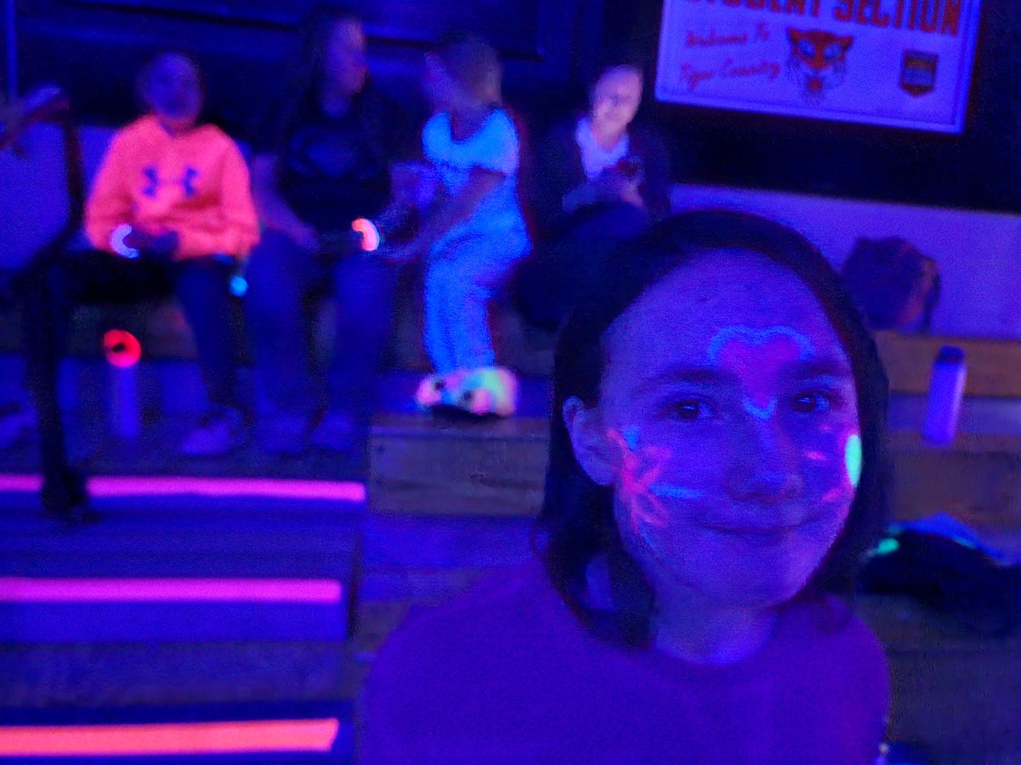 Face paint glowing under UV lights at Howard Tigers Blacklight Wrestling