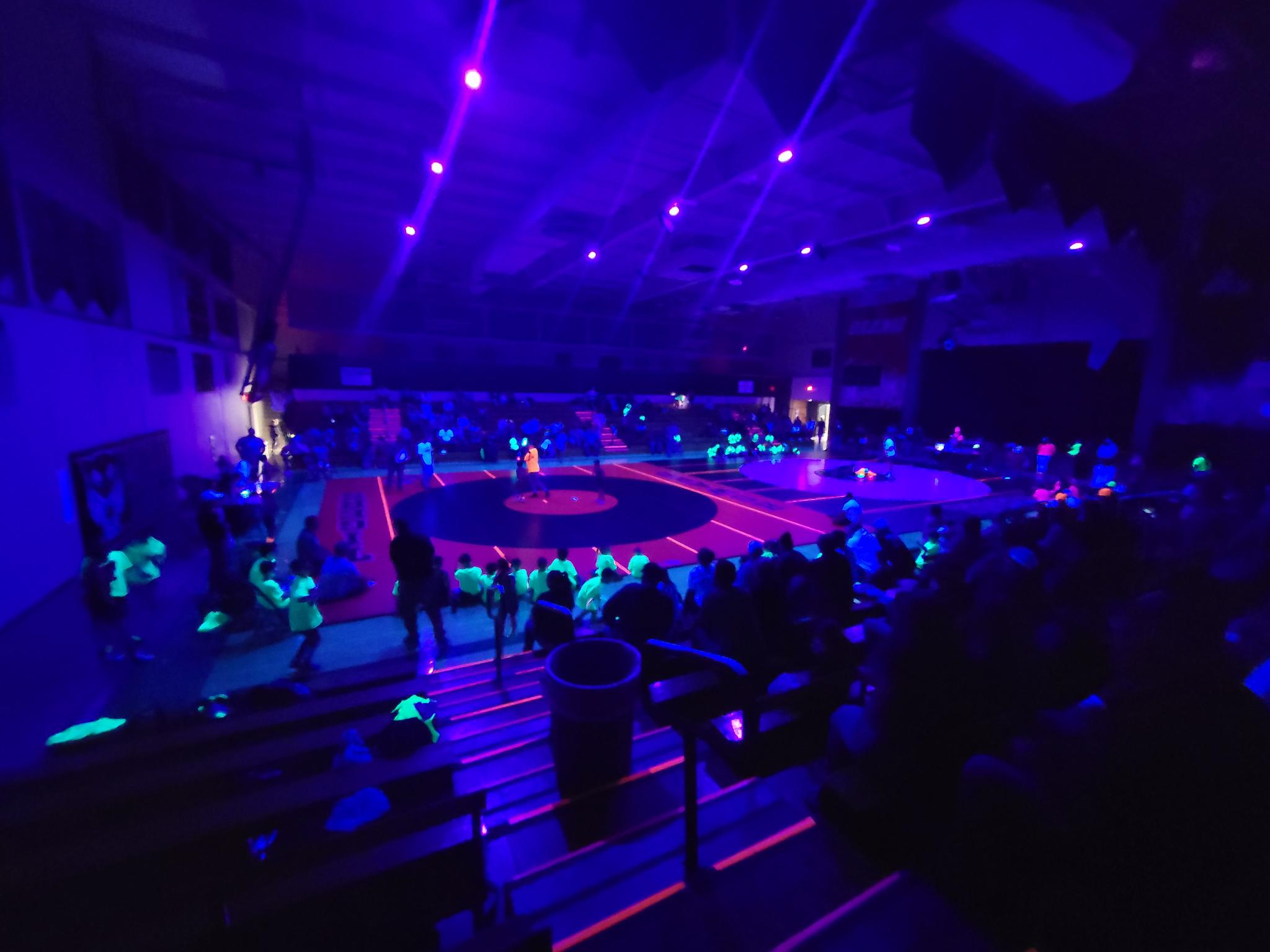Wide angle view of Howard Tigers Blacklight Wrestling with UV beams and haze